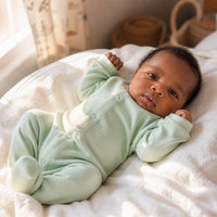 Nouveau-né portant une grenouillère en coton vert menthe dans une chambre de bébé à Dakar, lumière naturelle