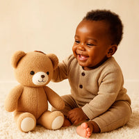 Bébé souriant jouant avec une peluche ours douce et sécurisée pour bébé, idéale pour les câlins et le sommeil, disponible chez NounaBaby à Dakar