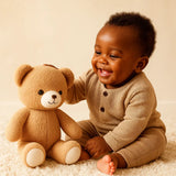 Bébé souriant jouant avec une peluche ours douce et sécurisée pour bébé, idéale pour les câlins et le sommeil, disponible chez NounaBaby à Dakar