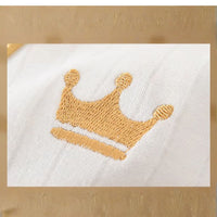 Broderie dorée en forme de couronne sur tissu coton du coffret naissance bébé NounaBaby – symbole de tendresse et de royauté, pour bébé fille ou garçon.