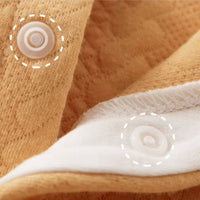 Détail du bouton pression sur combinaison bébé en coton doux, couture solide et confortable – qualité premium pour layette nouveau-né.