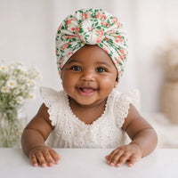 Bébé fille souriante portant un turban fleuri bohème – NounaBaby Dakar